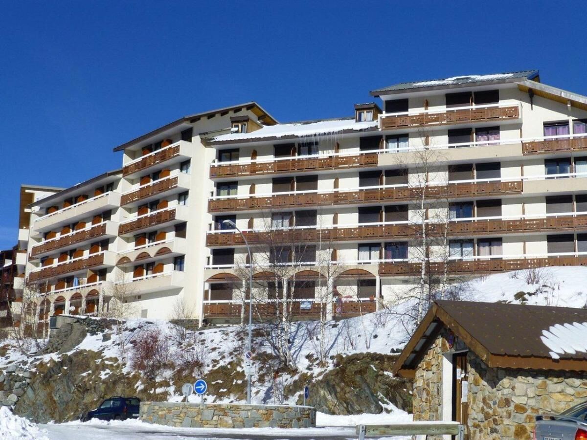 A multi-story hotel with balconies, stone walls, and a snowy landscape.