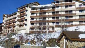 Un hotel de varios pisos con balcones, paredes de piedra y un paisaje nevado.