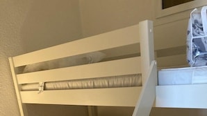 Una cama litera con escalera, ropa de cama blanca y una bolsa de plástico en la parte superior.