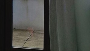 Une pièce avec vue sur un bâtiment et un plan d’eau, vue à travers une porte ouverte.