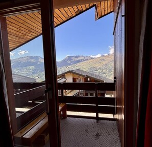 A wooden balcony with a view of a mountainous landscape.