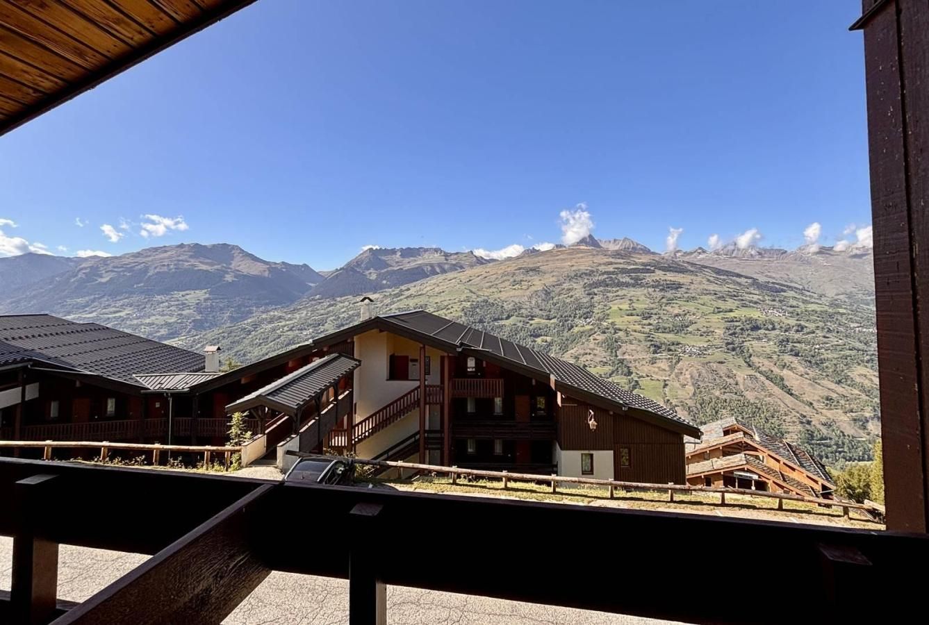 A mountain lodge with multiple buildings, a wooden deck, and a view of the surrounding mountains.