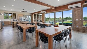 A spacious kitchen with wooden cabinets, a large island, and a dining area with black chairs and a wooden table.