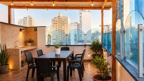 A rooftop terrace with a wooden table and chairs, potted plants, and a city view. - HOTEL SOUL MATE INN  (Lima)