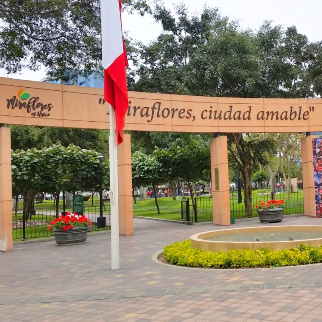 Un espace public avec une pancarte sur laquelle on peut lire « Miraflores, ville accueillante » et un mât sur lequel flotte un drapeau.