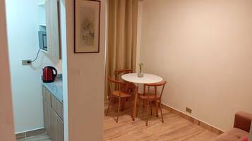 A compact living space with a kitchenette, a dining area with a table and four chairs, and a sofa.