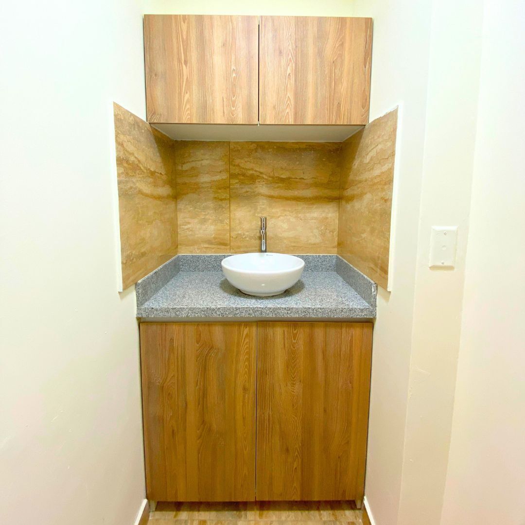 Un baño con tocador de madera, encimera de granito y lavabo blanco.