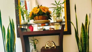 A reception area with a mirror, potted plants, a small elephant figurine, and a heart-shaped decoration on a console table. - HOTEL SOUL MATE INN  (Lima)
