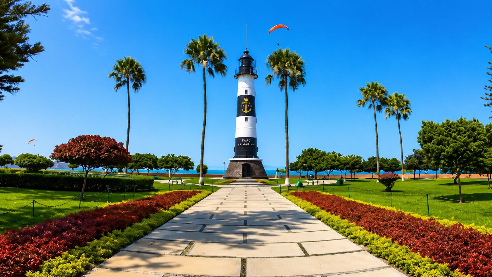 A lighthouse with a clear sky, surrounded by a well-maintained garden with red and green plants, and palm trees.