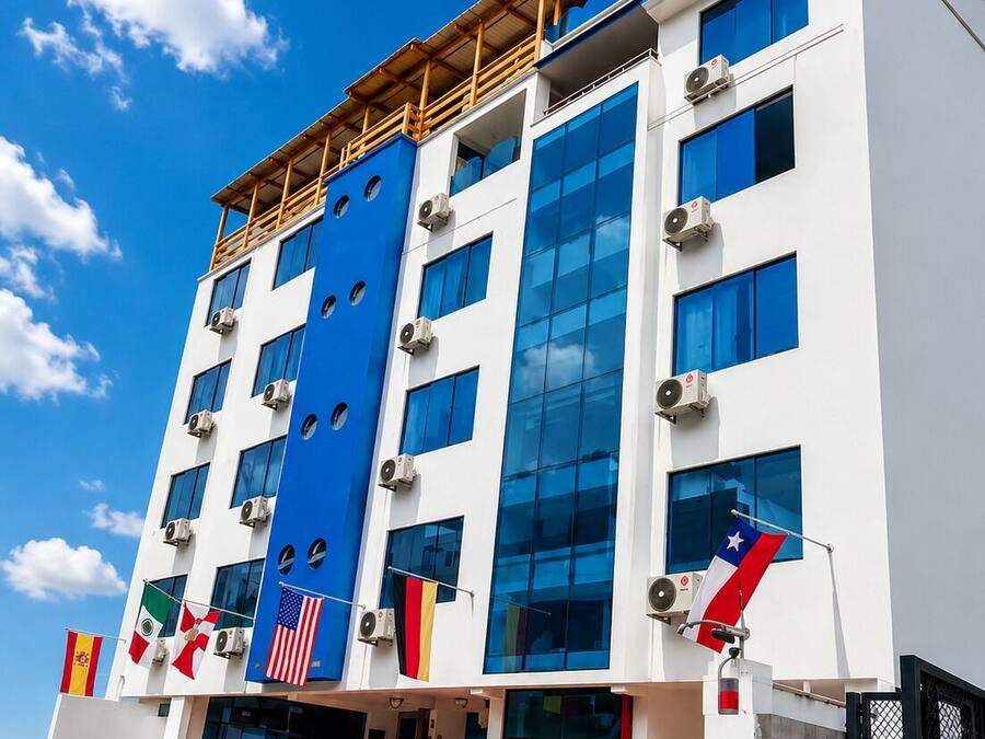 Um edifício de vários andares com design arquitetônico moderno, destacando um esquema de cores azul e branco, várias unidades de ar condicionado e uma exibição de bandeiras.