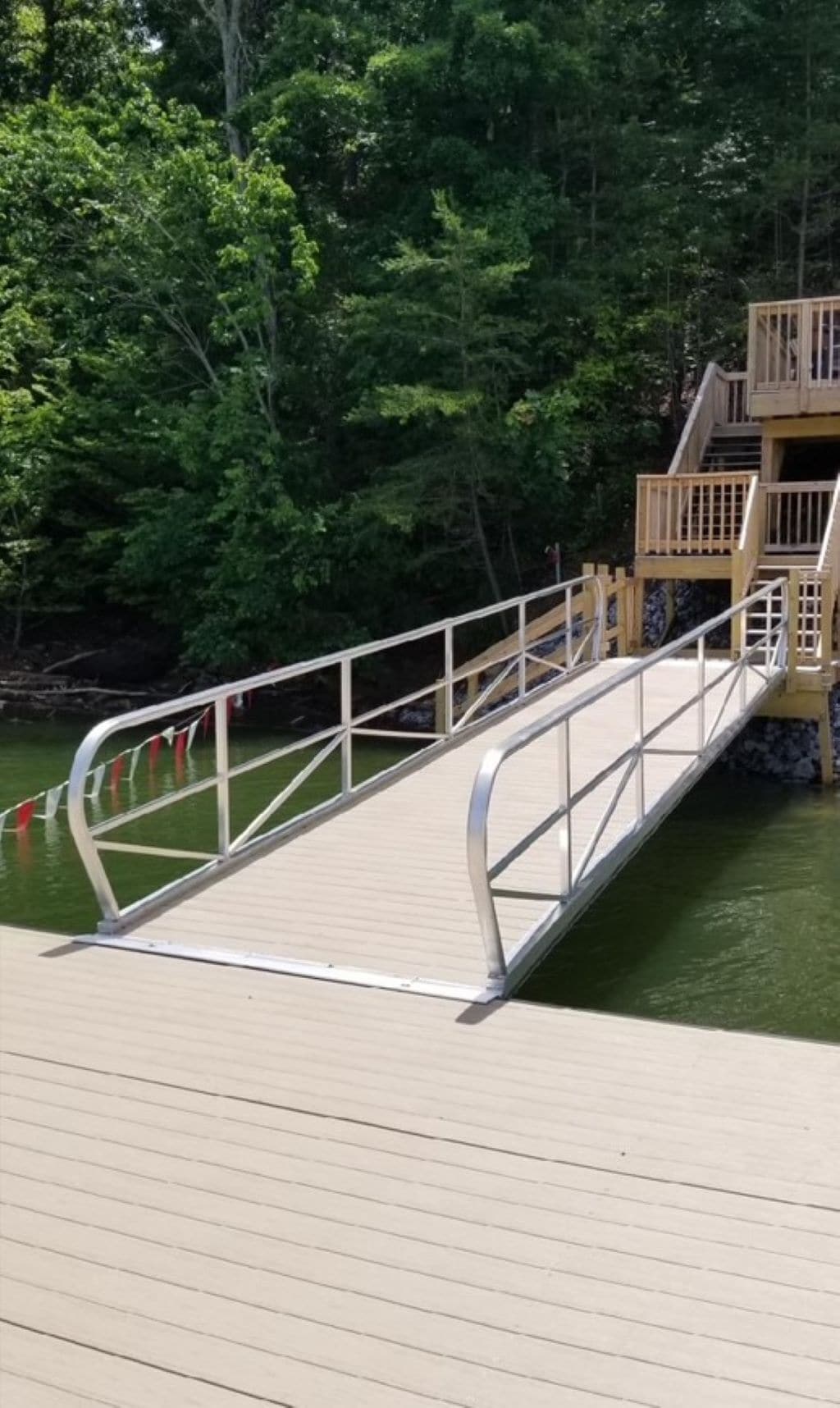 Eine Holzsteganlage, die sich über das Wasser erstreckt, mit Metallgeländern und einer Holztreppe, die zu einer Plattform führt.