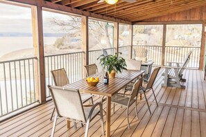 A covered outdoor dining area with a wooden table, chairs, and a potted plant.