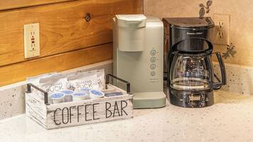 A kitchenette with a coffee maker, a Procter & Silvers coffee pot, and a coffee bar sign.