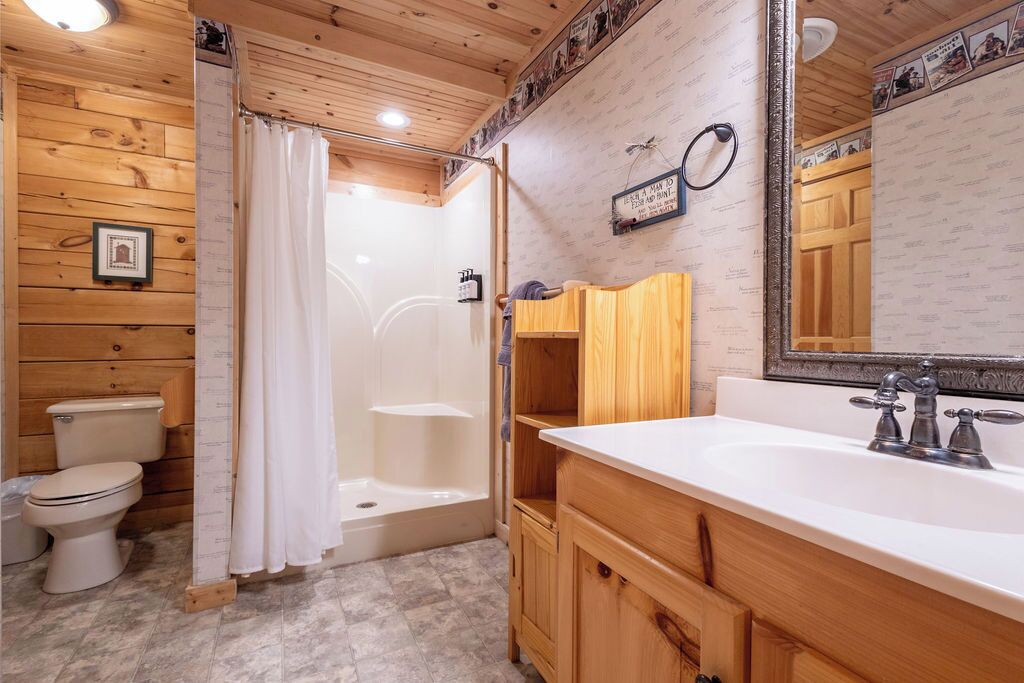 A wooden-paneled bathroom with a shower, toilet, and vanity.