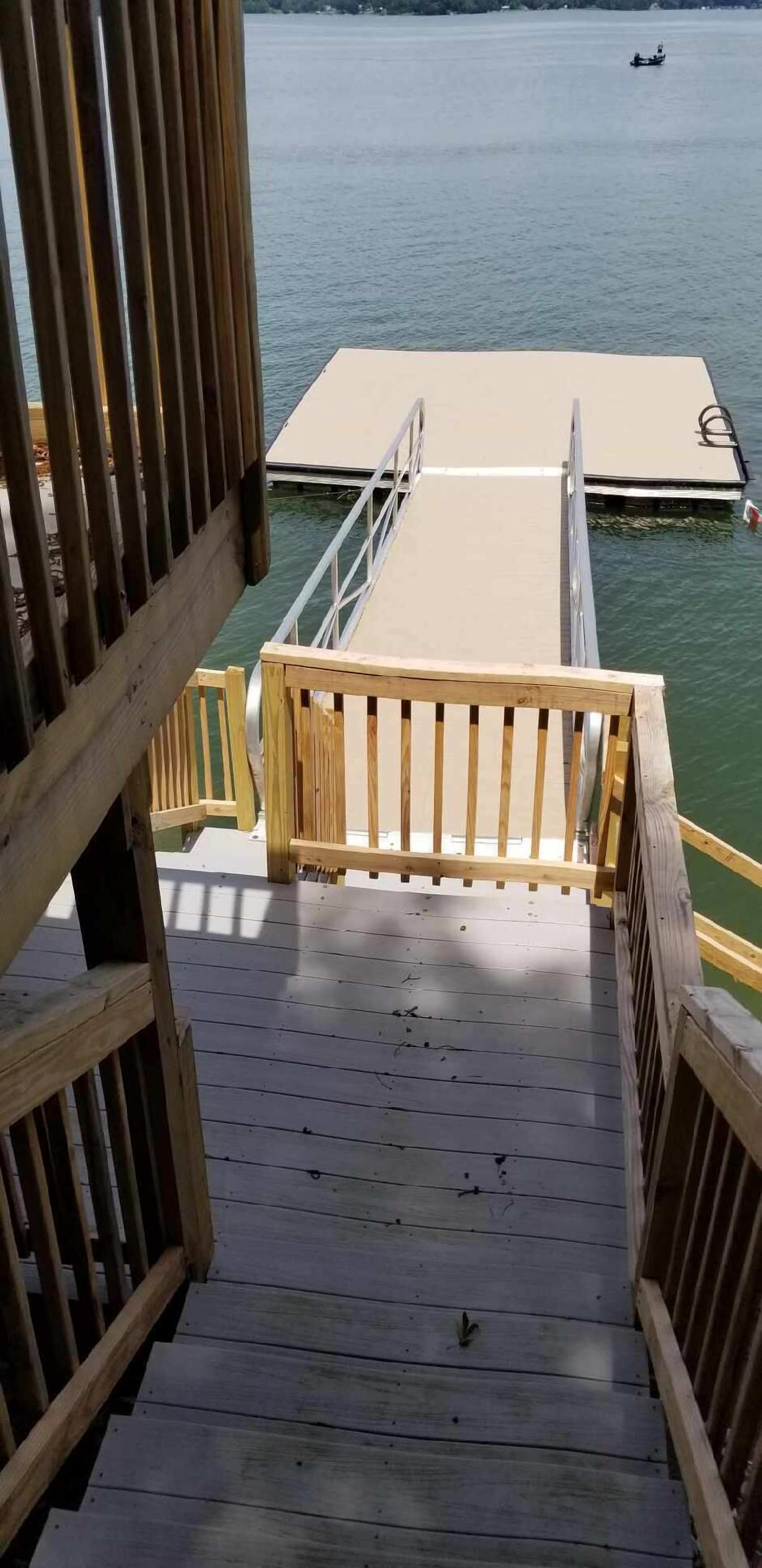Une terrasse en bois qui mène à une jetée surplombant l’eau.