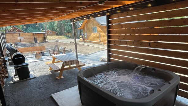 Uma banheira de hidromassagem sob uma pérgola de madeira com vista para um espaço de pátio nos fundos.