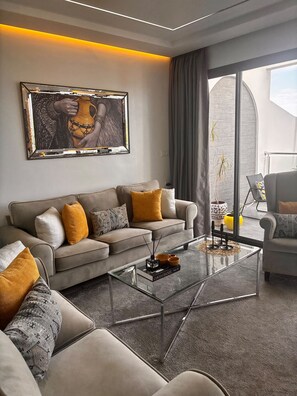 A modern living room with a sofa, coffee table, and a large window with curtains.