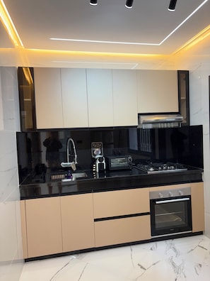 A modern kitchen with a black countertop, stainless steel appliances, and beige cabinetry.