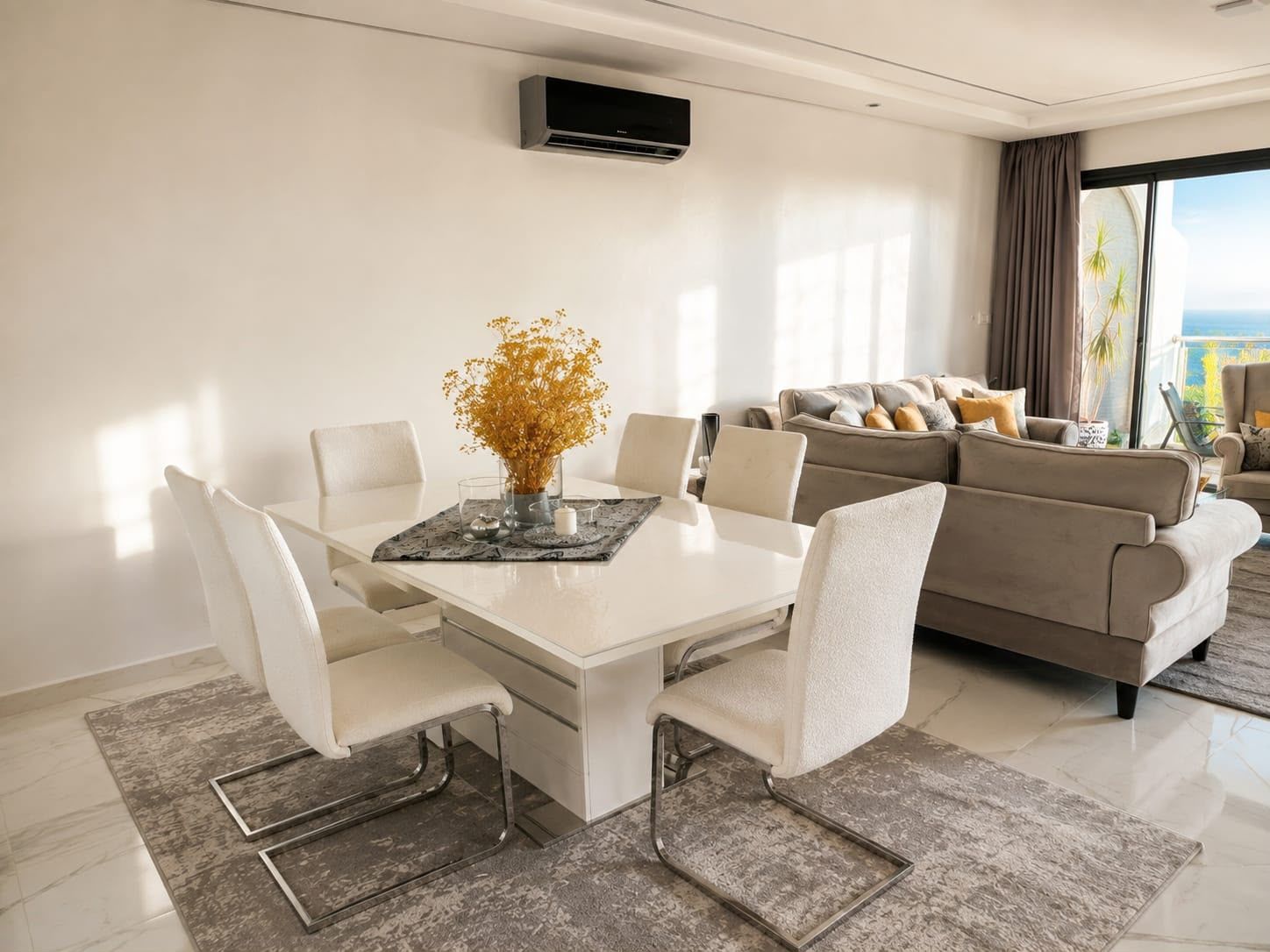 Uma sala de estar moderna com área de jantar, sofá e vista para o exterior.