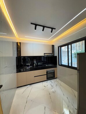 A modern kitchen with a marble floor, black countertops, and built-in cabinetry.
