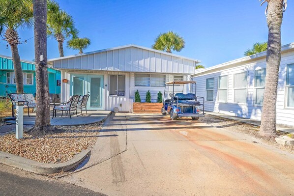 A mobile home with a porch, a golf cart, and a mailbox.