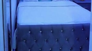 A bedroom with a tufted headboard, a bed with white and blue bedding, a nightstand with a lamp, and a ceiling light fixture. - Apt Private +WiFi+AC+Kitchen @Dominican Republic (Santiago Province)