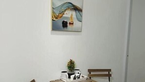 A small room with a wooden table and two chairs, a painting on the wall, and a small plant on the table. - Apt Private +WiFi+AC+Kitchen @Dominican Republic (Santiago Province)