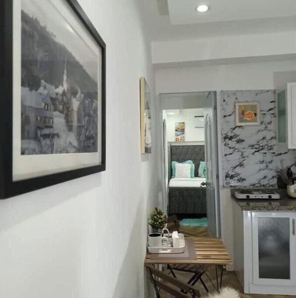 Une chambre à coucher moderne avec un lit, une table de chevet sur laquelle se trouve un plateau, et un tableau encadré accroché au mur.