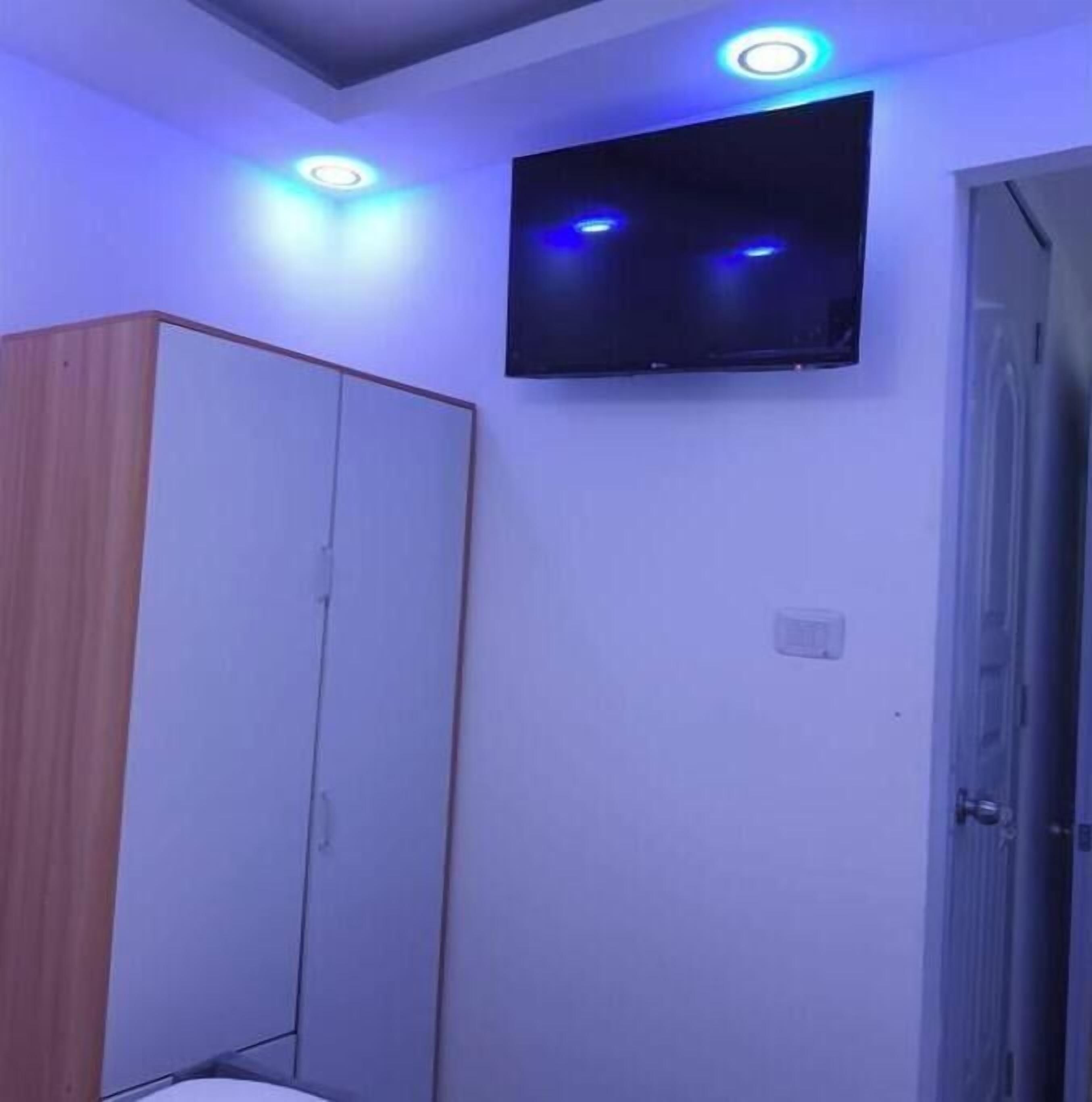 Een kamer met een aan de muur bevestigde televisie, een garderobe en inbouwverlichting.