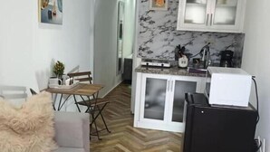 A compact living space with a kitchenette, a dining area, and a sofa with a fluffy throw. - Apt Private +WiFi+AC+Kitchen @Dominican Republic (Santiago Province)