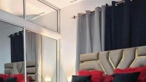 Een moderne slaapkamer met een groot bed, een hoofdbord met een geometrisch ontwerp en een spiegelkast.