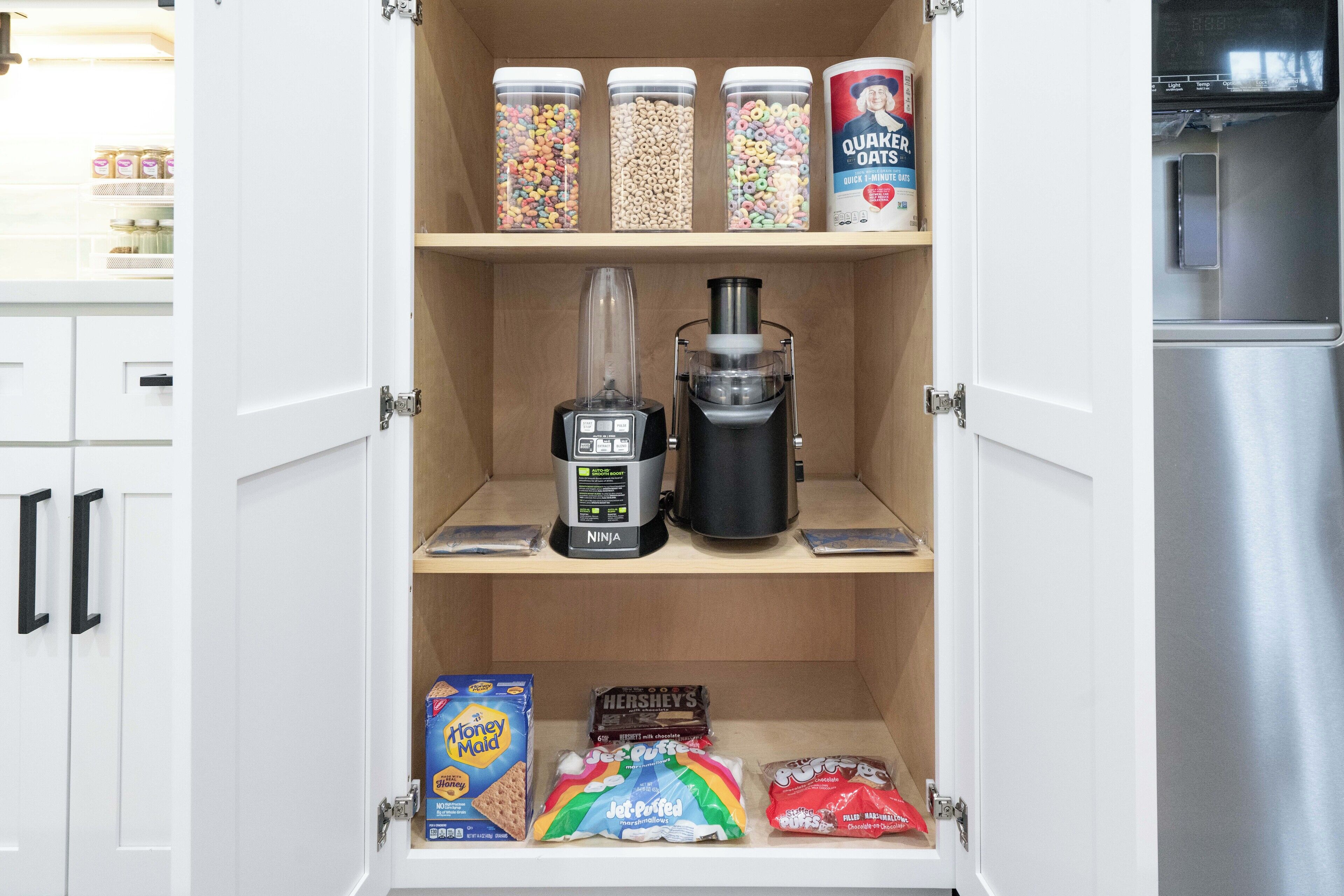 A kitchen pantry with storage jars, a blender, and various snacks.