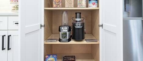 A kitchen pantry with storage jars, a blender, and various snacks.