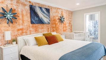 A bedroom with a bed, nightstands, a dresser, and a crib.