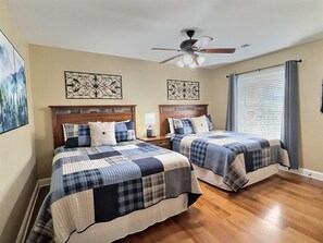 A bedroom with two beds, wooden headboards, a ceiling fan, and artwork on the walls. - Luxury Downtown Gatlinburg Condo – Walk to Parkway – Views, Pool – Sleeps 6 (Gatlinburg)