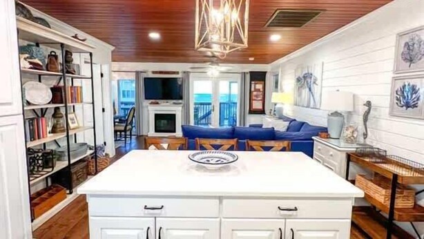 A kitchen with white cabinetry, a central island, and a hanging light fixture.