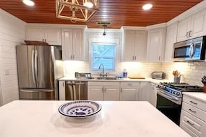 Una cocina moderna con armarios blancos, electrodomésticos de acero inoxidable y una isla central.