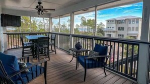 A covered outdoor area with a table and chairs, a ceiling fan, and a view of buildings and trees.