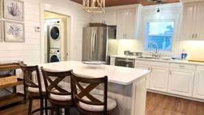 A kitchen with a central island, white cabinetry, and a wooden dining table with chairs.