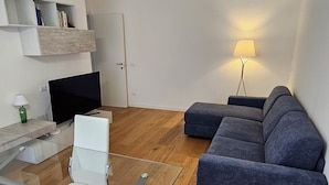 A modern living room with a sectional sofa, a glass coffee table, and a flat-screen TV. - Family apartment in the center of Pisa - Design LM House (Pisa)
