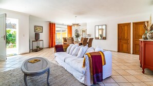 A spacious living room with a sofa, a dining table, and a TV. - 2 bedroom gorgeous home in Noves (Noves)