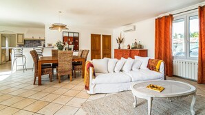 A living room with a sofa, dining table, chairs, and a round coffee table. - 2 bedroom gorgeous home in Noves (Noves)