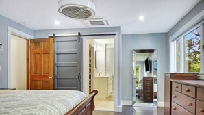 A bedroom with a bed, a wooden dresser, and a walk-in closet. - Spacious 5-bedroom lakefront home on pristine Lower Narrows Pond in Winthrop (Winthrop)