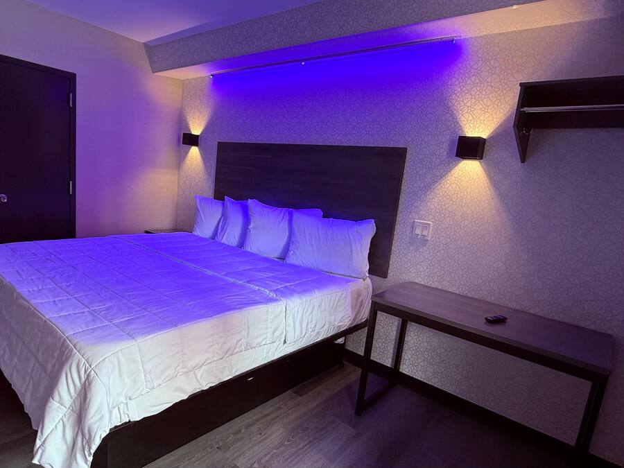 Een keurig opgemaakt slaapkamer met een groot bed, nachtkastjes en wandlampen.