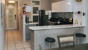 A modern kitchen with a central island, bar stools, and a dining table. - Full 1st Floor Apartment with Pool - La Parguera (Lajas)