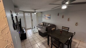 A dining area with a table and chairs, a sofa, and a ceiling fan. - Full 1st Floor Apartment with Pool - La Parguera (Lajas)