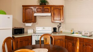 Una cocina compacta con armarios de madera, un microondas, un tostador y una estufa.