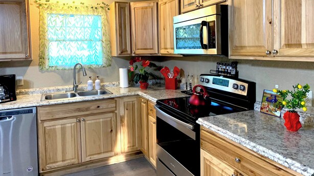 A kitchen with wooden cabinets, a stainless steel sink, a microwave, and a stove. - Bohemian Home•King Bed•Long Stay•RV/Boat/Trailer Parking•RenFest (Magnolia)