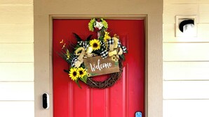 A red door with a 'Welcome' sign and a floral wreath. - Bohemian Home•King Bed•Long Stay•RV/Boat/Trailer Parking•RenFest (Magnolia)