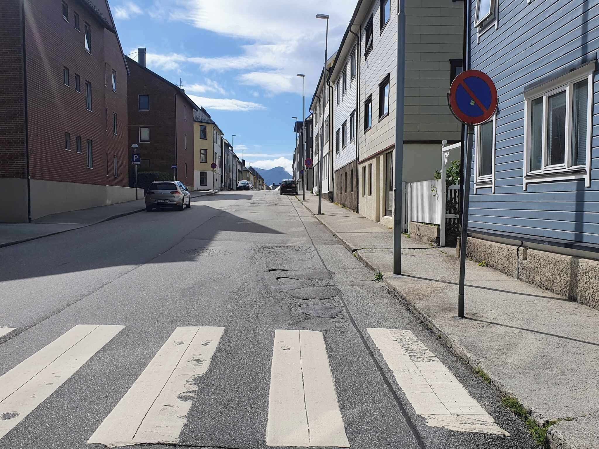 Une rue avec un passage piéton et des voitures garées.